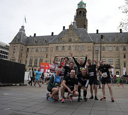 Active group of marathon runners celebrating in front of historic city hall during a corporate team-building event.