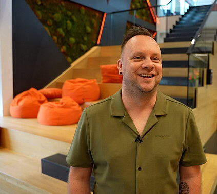 Diverse professional smiling man in modern office environment, modern workspace, modern office interior, professional workplace, collaborative office setting, comfortable work environment, vibrant office design, innovative workspaces, positive work culture.