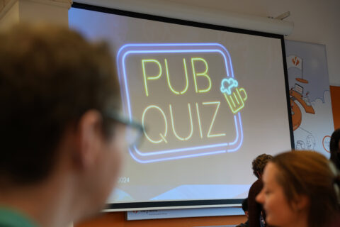 Neon PUB QUIZ sign displayed on a screen at a corporate event, promoting fun team activities and employee engagement for careers at Keylane.