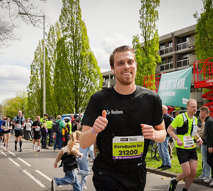 Active man running in marathon event, Keylane branded runner participating in race, vibrant outdoor marathon scene with supporters and runners, promoting health and corporate team spirit.